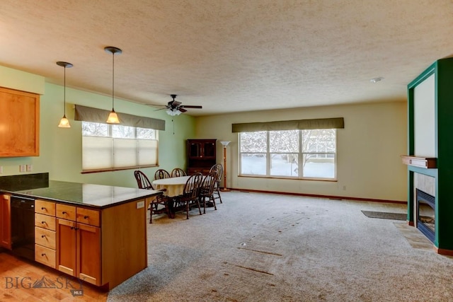 kitchen with light carpet, kitchen peninsula, ceiling fan, a tile fireplace, and black dishwasher