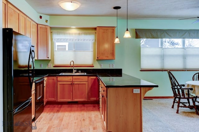 kitchen with light wood-type flooring, a breakfast bar, sink, black appliances, and decorative light fixtures