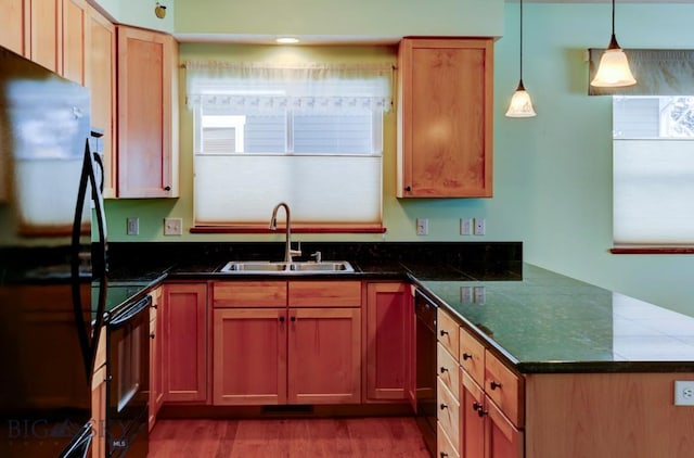 kitchen featuring kitchen peninsula, dark hardwood / wood-style flooring, black appliances, sink, and pendant lighting