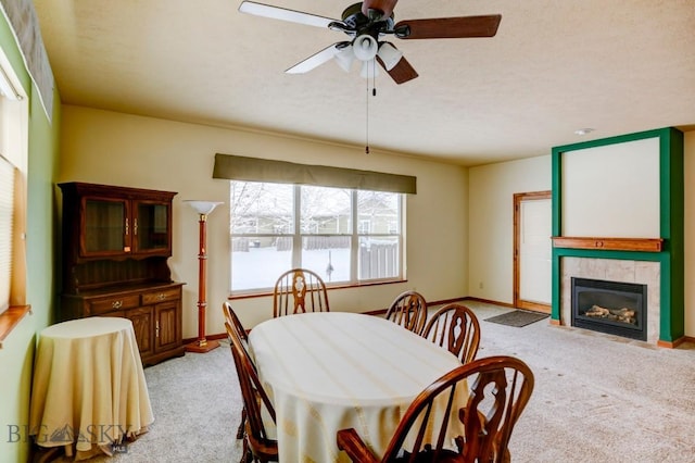 carpeted dining space with ceiling fan and a fireplace