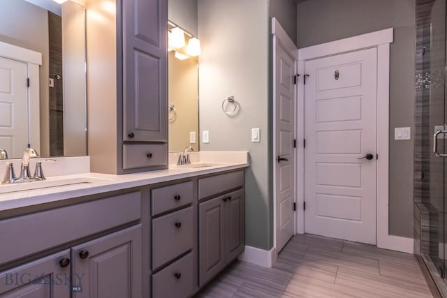 full bathroom featuring a sink, baseboards, double vanity, and a stall shower