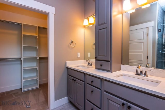 full bathroom with double vanity, baseboards, and a sink