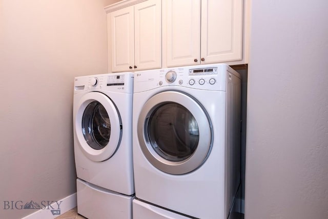 clothes washing area with separate washer and dryer, baseboards, and cabinet space