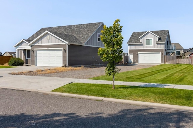 view of front of home with board and batten siding, fence, a front lawn, an attached garage, and driveway