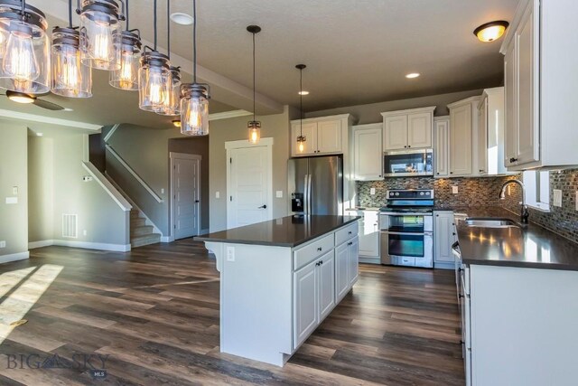 kitchen featuring appliances with stainless steel finishes, a center island, white cabinetry, and dark wood-type flooring