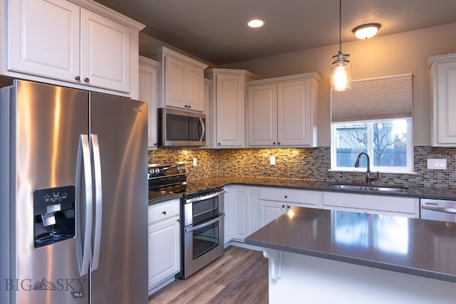 kitchen with dark countertops, a sink, white cabinets, and stainless steel appliances