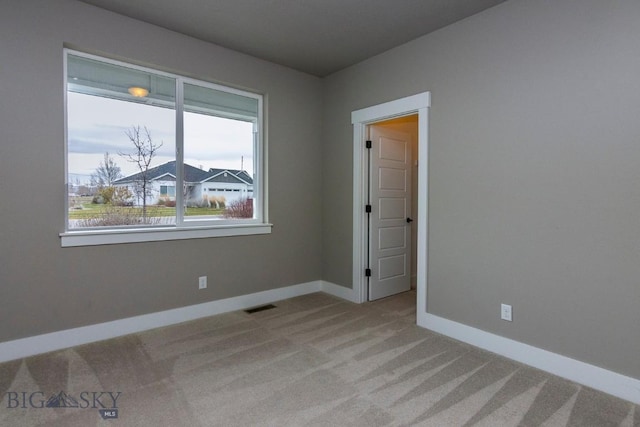 empty room with light colored carpet, baseboards, and visible vents