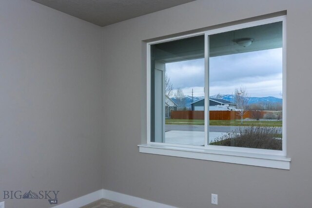 unfurnished room featuring a wealth of natural light and a mountain view