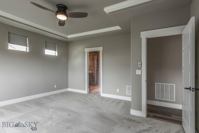 spare room featuring visible vents, ceiling fan, a tray ceiling, and baseboards