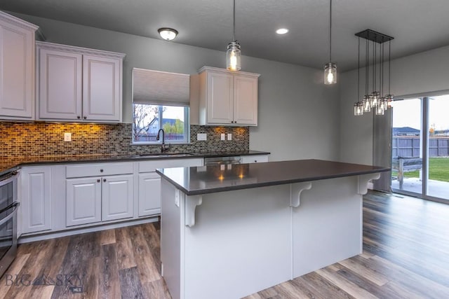 kitchen featuring dark wood finished floors, dark countertops, backsplash, and a breakfast bar
