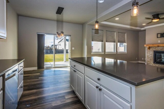 kitchen featuring decorative light fixtures, dishwasher, dark hardwood / wood-style floors, white cabinetry, and a stone fireplace