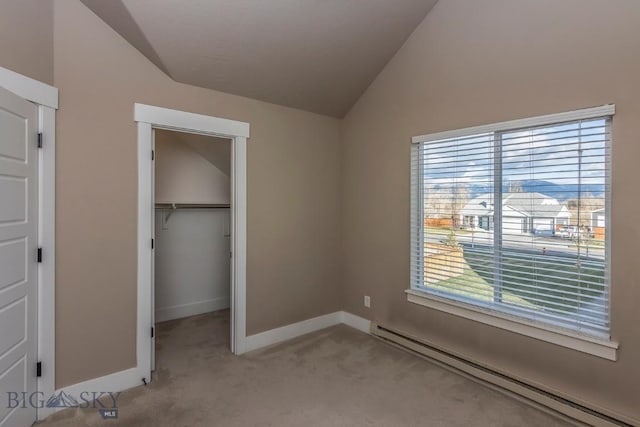unfurnished bedroom featuring light colored carpet, a spacious closet, baseboard heating, lofted ceiling, and baseboards