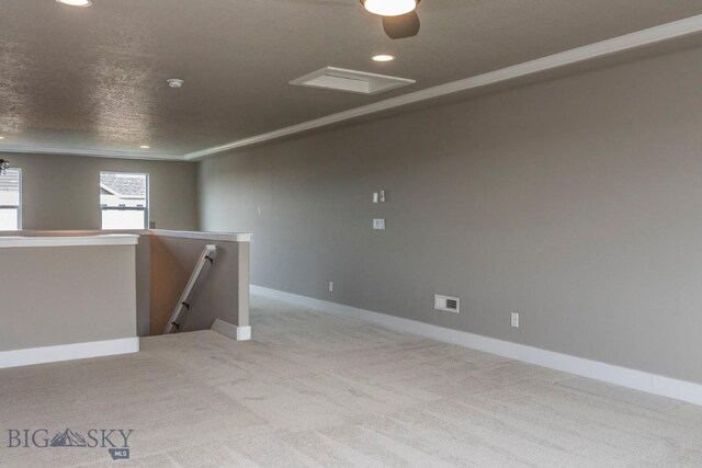 spare room with a textured ceiling, crown molding, and light carpet