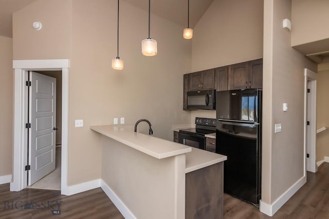 kitchen with light countertops, a peninsula, dark wood finished floors, black appliances, and high vaulted ceiling