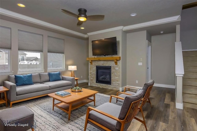 living area featuring a stone fireplace, baseboards, crown molding, a ceiling fan, and wood finished floors