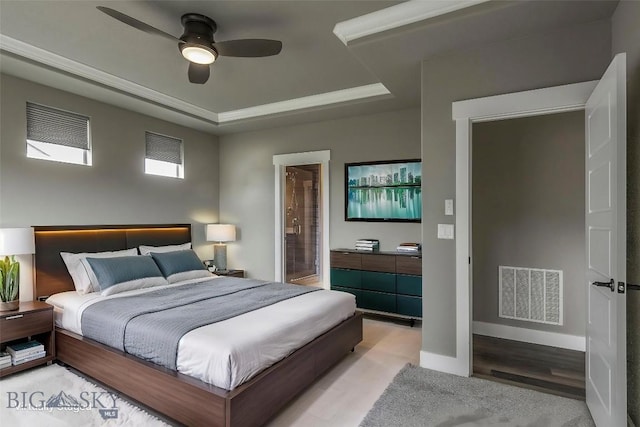 bedroom featuring light wood-style floors, ceiling fan, visible vents, a raised ceiling, and baseboards
