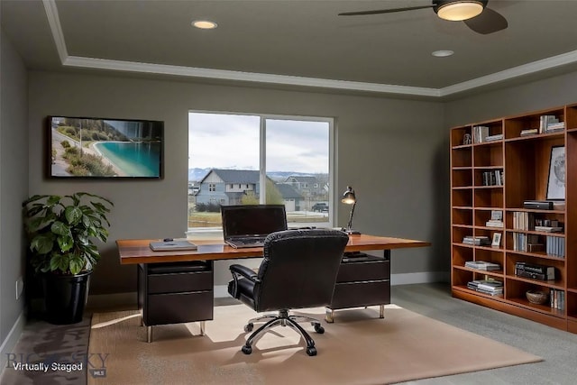 carpeted office space featuring ornamental molding, ceiling fan, a tray ceiling, and baseboards
