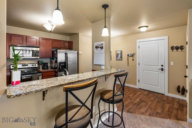 kitchen with stainless steel appliances, dark hardwood / wood-style floors, kitchen peninsula, pendant lighting, and a breakfast bar