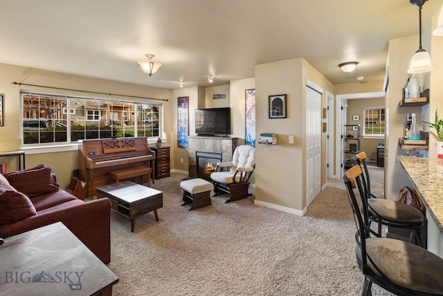 living room with a tiled fireplace, plenty of natural light, and carpet floors