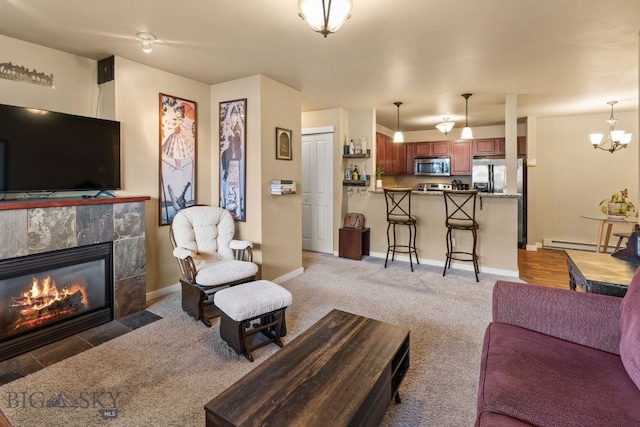 living room with a notable chandelier, carpet floors, a tile fireplace, and a baseboard radiator