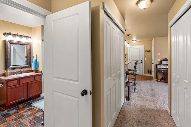 corridor featuring dark colored carpet and sink