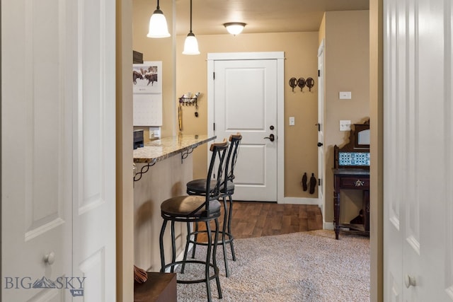 interior space featuring dark hardwood / wood-style floors, light stone counters, and hanging light fixtures