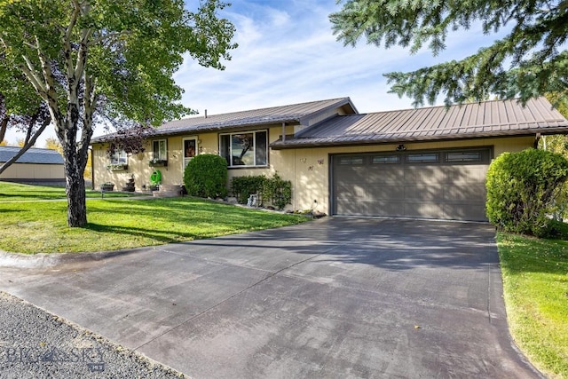 ranch-style house with stucco siding, a front lawn, metal roof, concrete driveway, and a garage