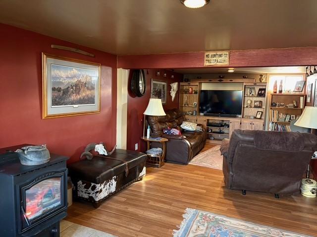 living room with hardwood / wood-style flooring, built in features, and a wood stove