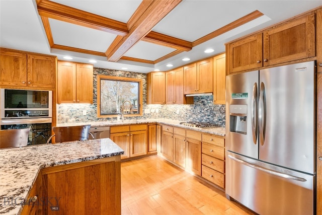 kitchen with appliances with stainless steel finishes, light wood-type flooring, light stone counters, and sink