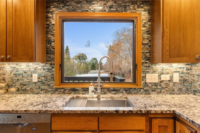 kitchen featuring light stone counters, stainless steel dishwasher, a healthy amount of sunlight, and sink