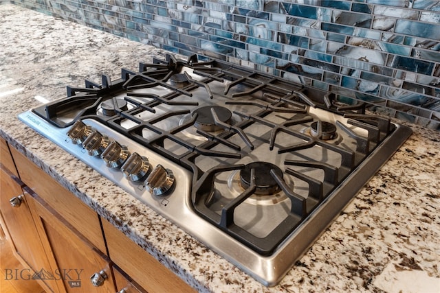 room details featuring stone counters, stainless steel gas cooktop, and tasteful backsplash