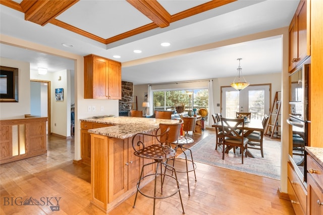 kitchen with light hardwood / wood-style floors, crown molding, light stone countertops, and hanging light fixtures