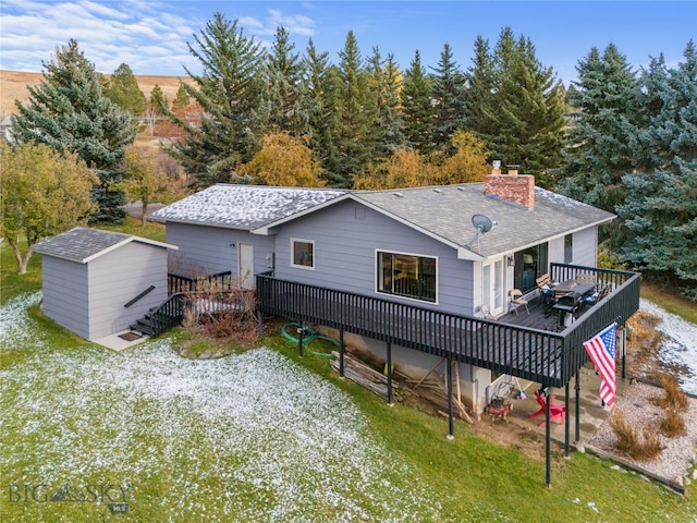 back of property with a deck and a storage shed