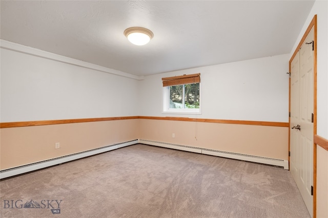 carpeted spare room with a baseboard heating unit