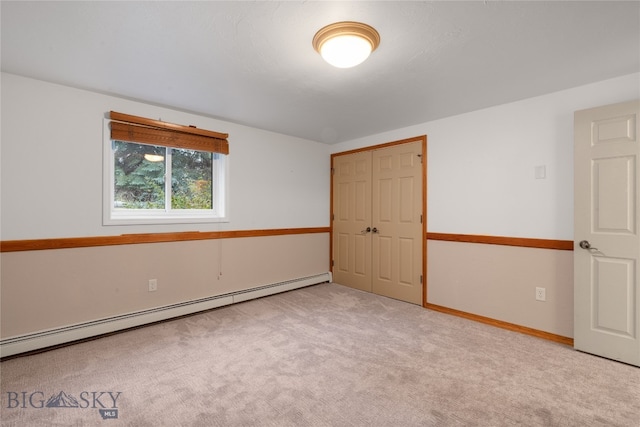 spare room with light carpet and a baseboard heating unit