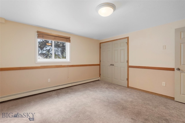 unfurnished bedroom featuring carpet floors, a closet, and baseboard heating