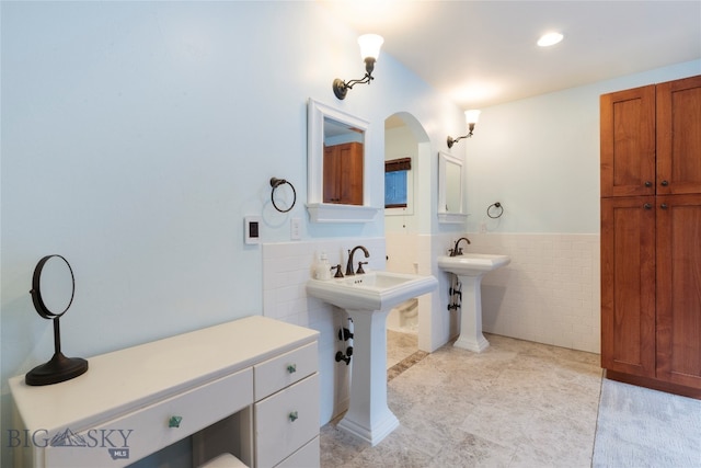 bathroom featuring tile patterned flooring, dual sinks, and tile walls