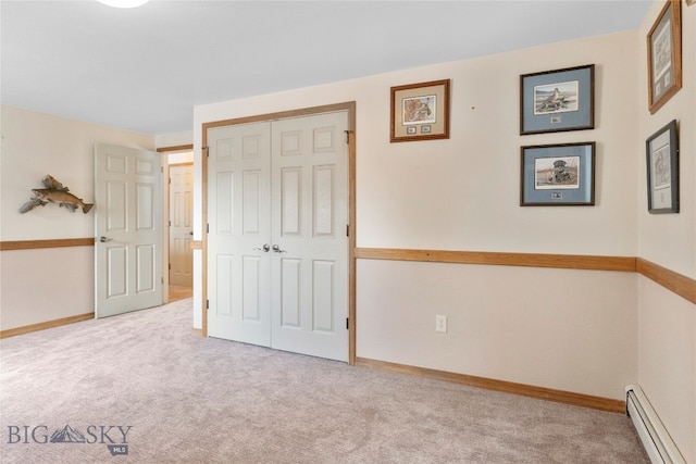 unfurnished bedroom featuring a closet, light colored carpet, and a baseboard heating unit