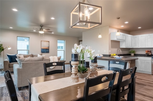 dining area with ceiling fan with notable chandelier and light wood-type flooring