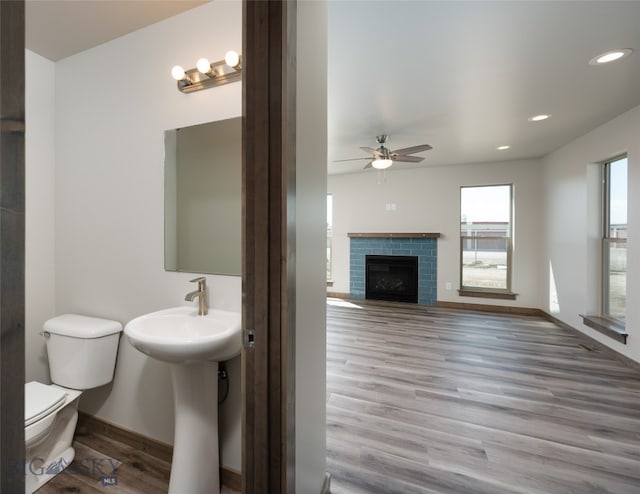 bathroom featuring hardwood / wood-style floors, ceiling fan, toilet, and a fireplace