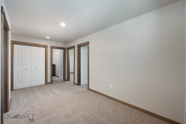 unfurnished bedroom featuring a closet and light colored carpet