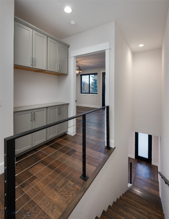 stairs featuring hardwood / wood-style floors and an inviting chandelier