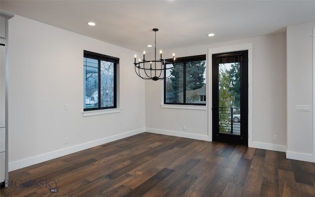 unfurnished dining area with dark hardwood / wood-style floors, a wealth of natural light, and a chandelier