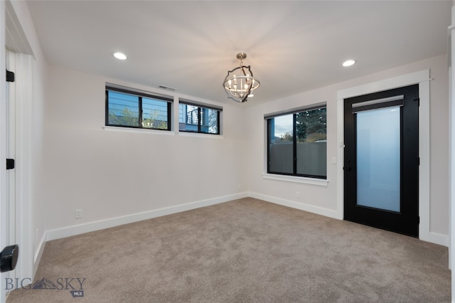 carpeted empty room with a chandelier