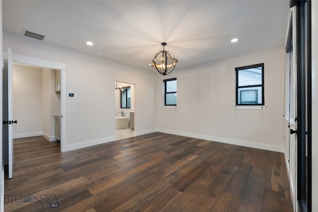 unfurnished room with a healthy amount of sunlight, dark hardwood / wood-style floors, and a notable chandelier