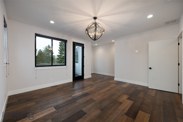 unfurnished room with dark hardwood / wood-style floors and an inviting chandelier