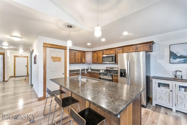 kitchen featuring a breakfast bar, sink, tasteful backsplash, pendant lighting, and stainless steel appliances