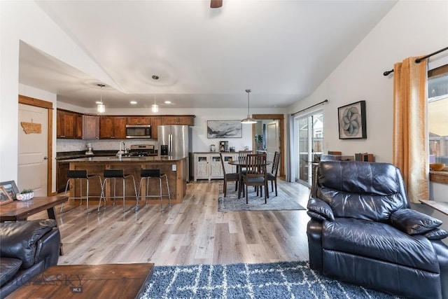 living room with lofted ceiling, sink, and light hardwood / wood-style flooring