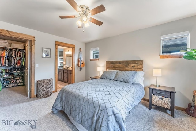 bedroom featuring a spacious closet, light colored carpet, ceiling fan, ensuite bath, and a closet