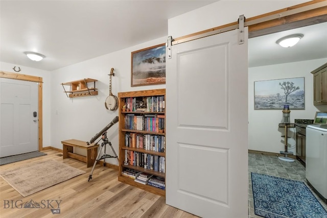 foyer entrance with a barn door and light hardwood / wood-style floors